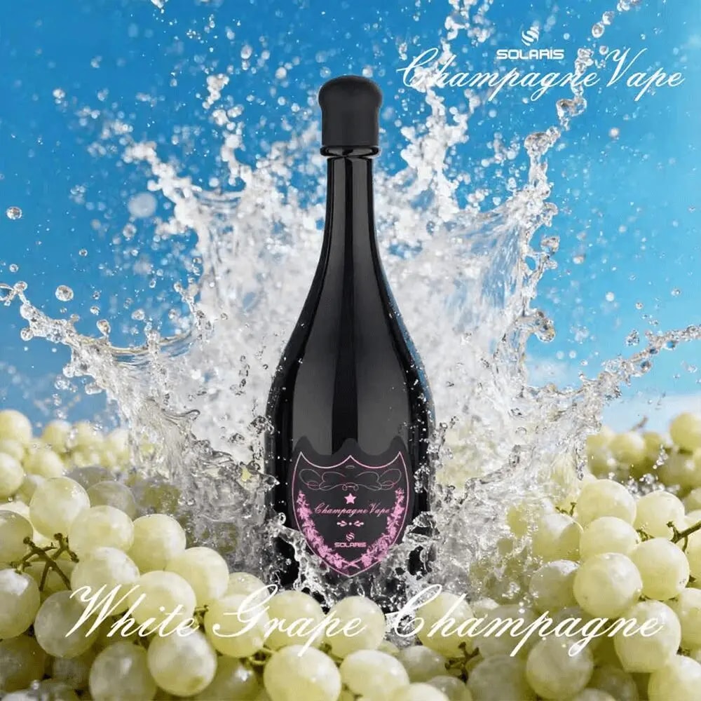En hög, mörk champagneflaska med en rosa etikett är stänkt av vatten och omgiven av vita druvklasar mot en klarblå himmel.