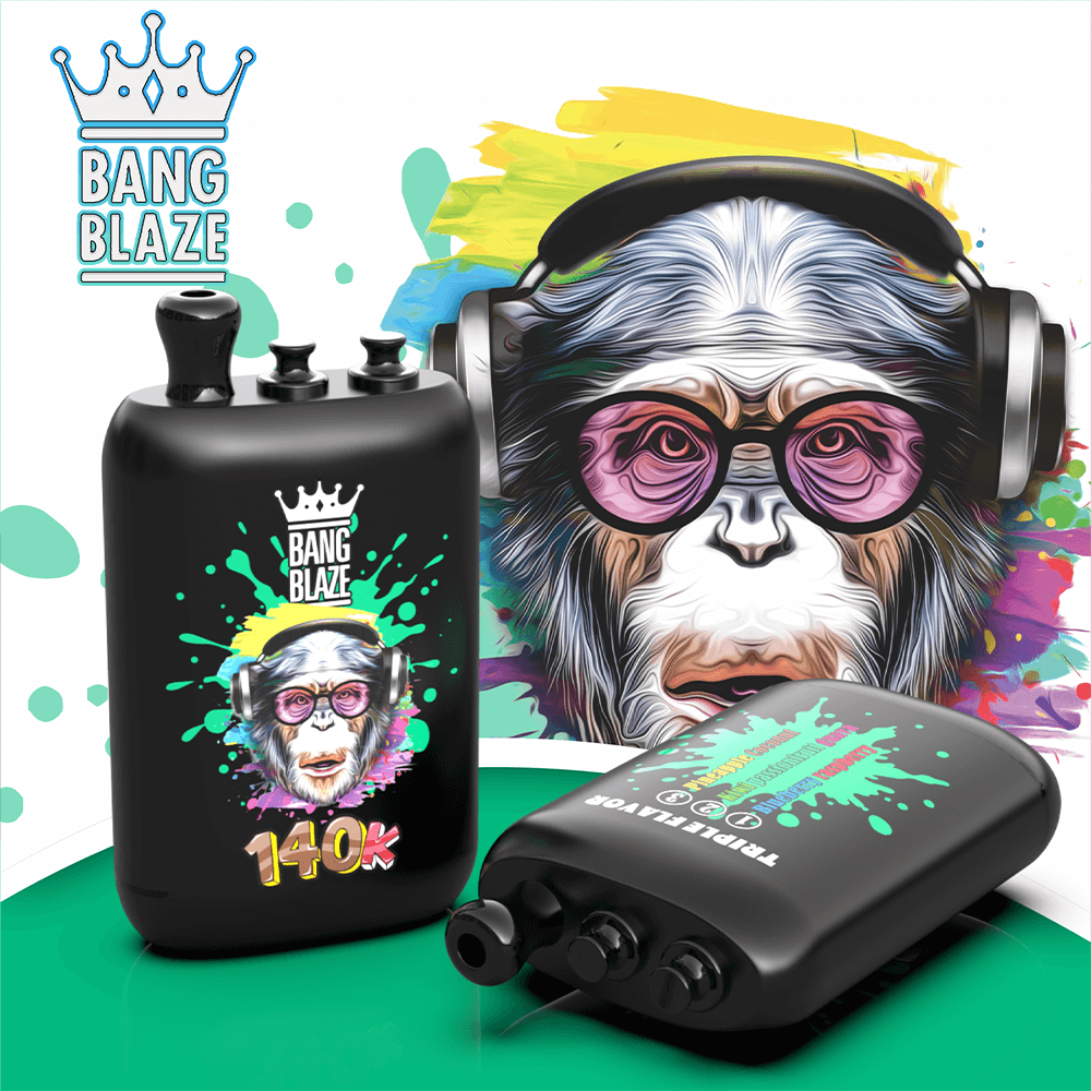 Bang Blaze bottle with crown logo and paint-splatter design, on a green surface with headphones nearby.