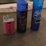 Three colorful vape devices are placed on a table: a small red and silver one labeled "Volt Cube," a blue one labeled "Bang Box" with a monster graphic, and a taller blue device labeled "Bang Beach" featuring another monster design.