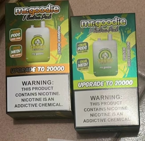 Två lådor med "mr.goodie" vaping-enheter för engångsbruk, märkta "Upgrade to 20000", med varningar om nikotinberoende och smakerna "Lemon Rainbow" och "Frozen Watermelon".